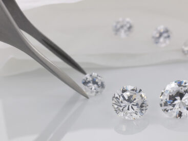diamanti acquistati in sicurezza con pinzette su fondo bianco
