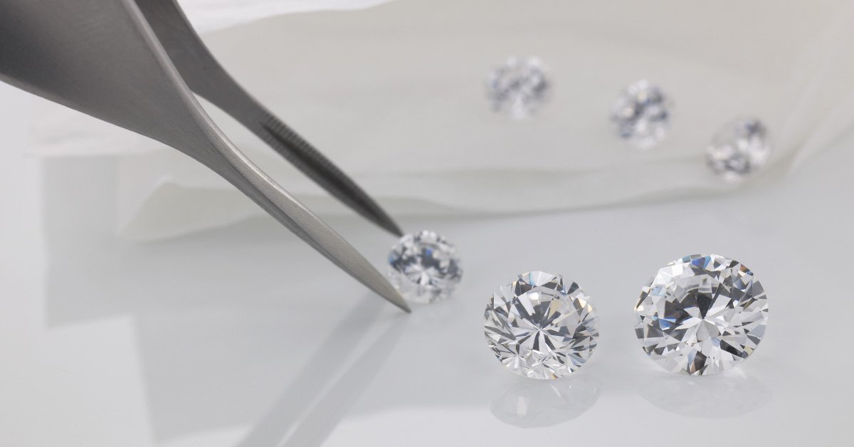 diamanti acquistati in sicurezza con pinzette su fondo bianco